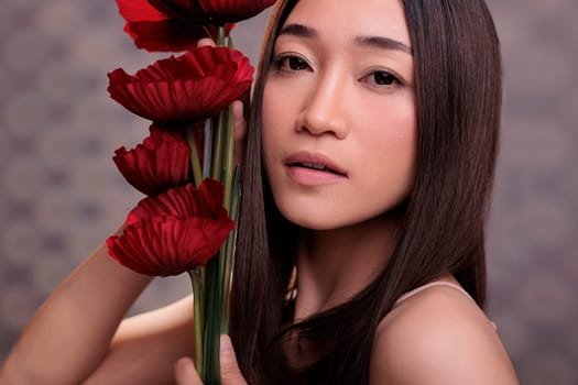 Cosmetology model with perfect skin posing with poppies bouquet