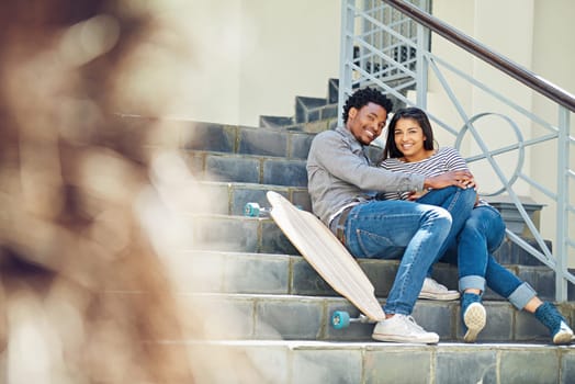 Couple, happy and skateboard while sitting on stairs with hug, love and romance in city sunshine. Black couple, urban happiness and outdoor with skater, embrace and romance on steps in San Francisco