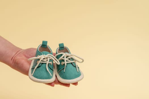 Children's shoes on a woman's palm. The idea of motherhood and the expectation of a newborn