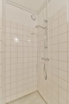 a shower in a white tiled bathroom with white