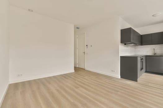 an empty living room with a kitchen in the corner