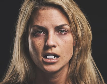 Woman, face and pill for drug in addiction for substance abuse to cure pain and suffering over black studio background. Portrait of female addict or model addicted to medical pills, help and rehab