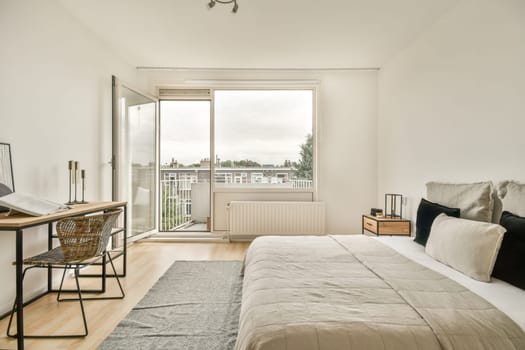 Amsterdam, Netherlands - 10 April, 2021: a bedroom with a bed, desk and window looking out onto the cityscapearron comcome