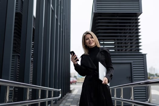 a business woman holds a phone in her hand and speaks with a partner on a cellular connection against the backdrop of a business center