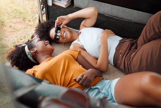 Women, camper and happy lying down on road trip, travel or vacation together in summer, holiday or break. Black woman, friends and smile at funny, crazy or comic time while relax in transport to rest