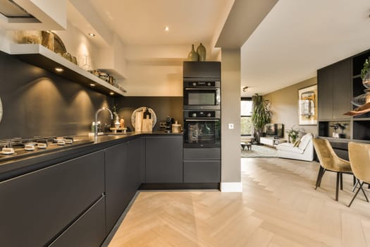 a modern kitchen with wood flooring and black cabinets in the center of the room is an open dining area