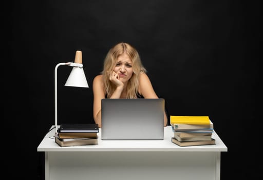 Frustrated, sad, stressed or depressed woman feeling tired while working with a laptop on a black background.