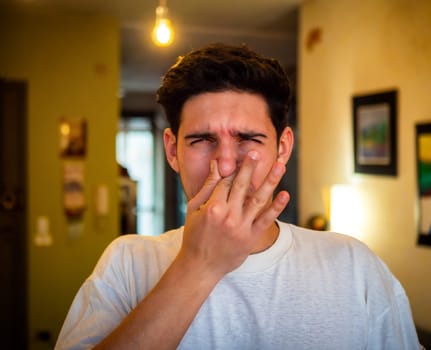 Disgusted man pinching nose in blurred room