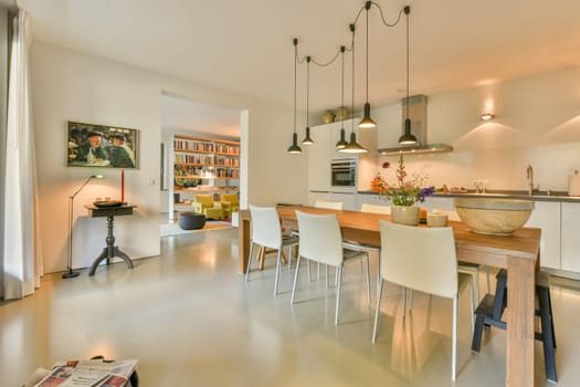 a kitchen and dining area in a modern living room with white walls, hardwood flooring and an island table