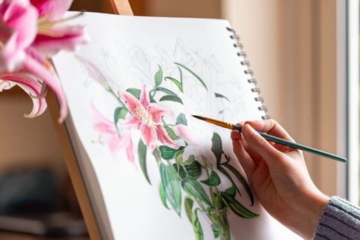 Young girl painting still life with flowers, purple lilies, with watercolor paints on the easel