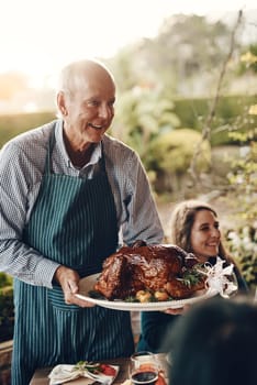 Chicken, celebration and man serving lunch on Christmas holiday, family gathering and event in a backyard. Food, cooking and chef with a turkey for hungry people at a Thanksgiving dinner party