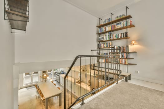 a living room with books on the shelves and a staircase leading up to the second floor in this modern home