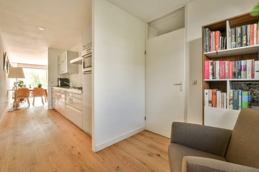 Amsterdam, Netherlands - 10 April, 2021: a living room with wood flooring and bookshels on the shelves in front of the door to the kitchen