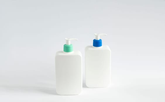 Two white unbranded dispenser bottles on white background. Cosmetic packaging mockup with copy space.