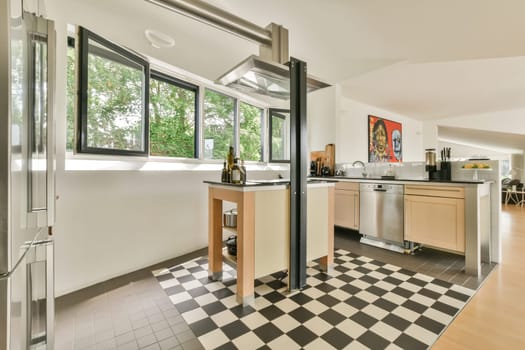 Amsterdam, Netherlands - 10 April, 2021: a kitchen area with black and white checkered tiles on the floor next to an open window that looks out onto trees