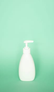 White plastic soap dispenser pump bottle on pastel green background. Skin care lotion, shampoo bottle, bath and body lotion. Bathroom Accessories.