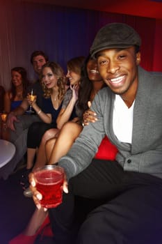 Tipsy and happy. A handsome african american man smiling happily while out clubbing with his friends.