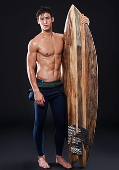 Live to surf. Full length studio shot of a young surfer with a vintage board.