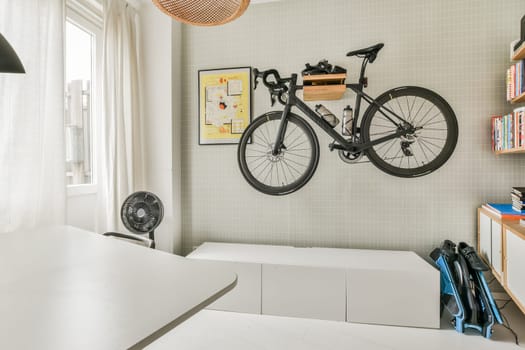 Amsterdam, Netherlands - 10 April, 2021: a bike mounted on the wall above a desk and bookshel in a home office space with white tile walls