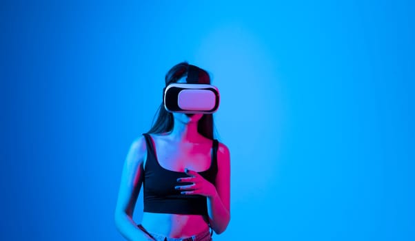 Brunette woman wearing virtual vr goggles. Young famale in a black top wearing virtual reality headset. VR concept.
