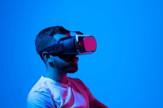 Bearded man in white t-shirt wearing Virtual Reality VR Headset ang playing a game online. VR for gaming. Man play game in VR glasses.