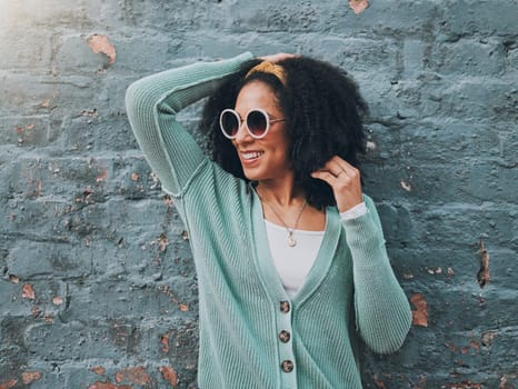 Brazilian woman, fashion and sunglasses by city building wall for fun summer holiday, weekend break or urban vacation. Smile, happy student or afro tourist in trendy, cool clothes and style eye care