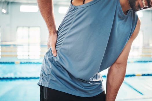 Sports, back pain and man by swimming pool with muscle ache, injury and arthritis inflammation. Health, medical care and athlete with accident, emergency or bruise from fitness, exercise or training