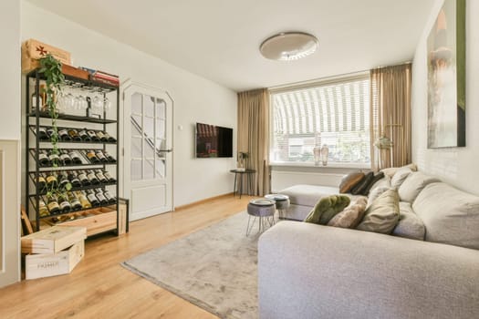 Amsterdam, Netherlands - 10 April, 2021: a living room with wood flooring and white walls there is a wine rack on the wall in front of the couch
