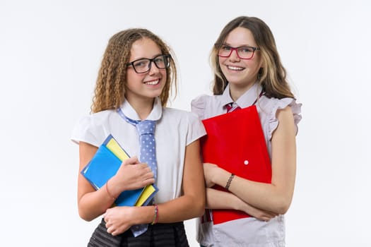 Two smiling high school girls with notebooks posing on white background