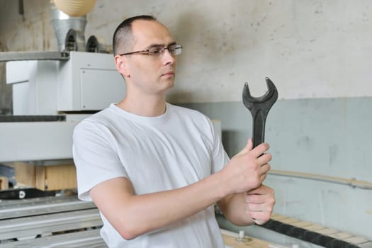 Portrait of industrial worker with tool, workman holding wrench or spanner.