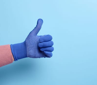 Female hand in blue work protective glove shows the gesture like on a blue background