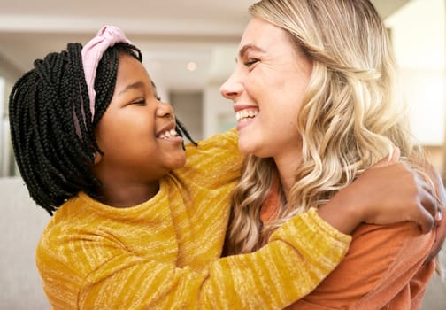 Mother, adopted and daughter bonding or hugging with love, care and affection for childhood embrace. Diverse woman and foster little girl hugging and having fun while in the family home