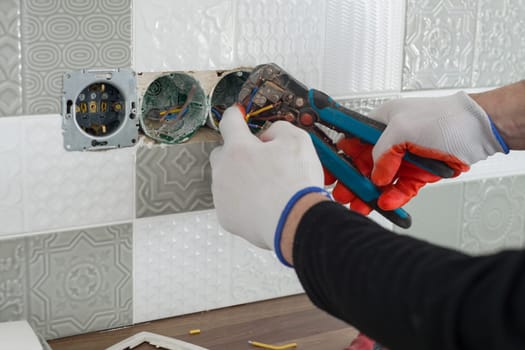 Close-up of electricians hand installing outlet on wall with ceramic tiles