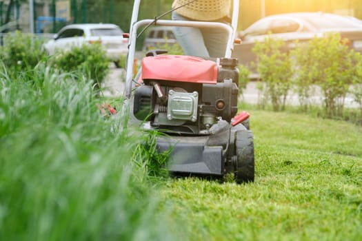 Lawn mower cutting green grass, gardener with lawnmower working