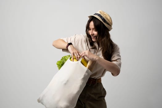 Woman holding textile grocery bag with vegetables. Zero waste concept. Package-free food shopping. Eco friendly natural bag with organic fruits and vegetables.
