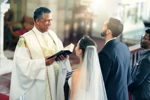Wedding, couple and priest with a bible in church praying to God with a Christian pastor reading the holy book. Love, bride and groom say an oath for a faithful and spiritual marriage commitment