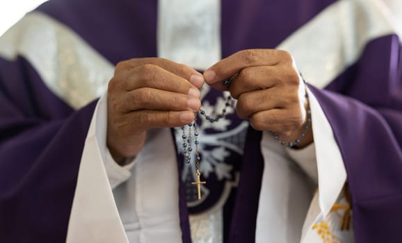 Priest, pastor and man hands with rosary with cross in church, prayer and catholic worship, praying or spiritual respect. Christian preacher, faith beads with crucifix and holy religion for God mercy