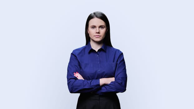 Serious young woman with crossed arms posing over white background