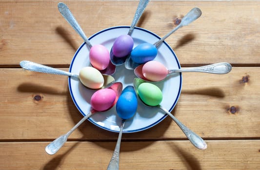 Close-up of colorful Easter eggs in spoons on a wooden background