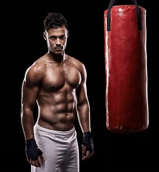 The warrior is always ready for battle. Studio shot of kick boxer working out with a punching bag against a black background.