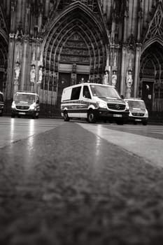 Grayscale shot of many Mercedes-Benz Sprinter police cars in front of Cologne Cathedral in Germany