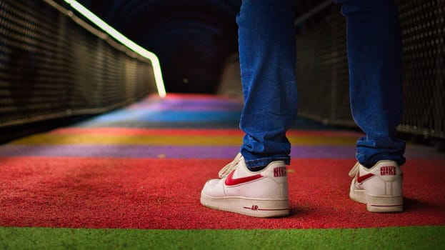 Guy wearing Nike sneakers and denim pants is standing on a rainbow trail