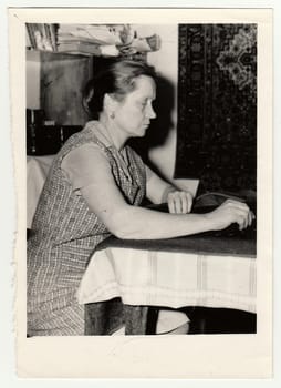 Vintage photo shows woman prepares to sew a dress.