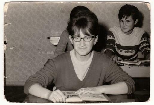 Vintage photo shows female pupil at the desk in the classroom.