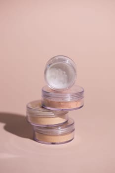 Mineral powder of beige and tan colors on pale rose colour background with shadows - beauty and make up concept