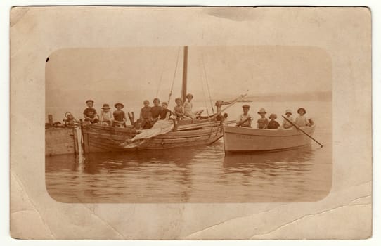 Vintage photo shows children on a boat trip. Antique black white photo with sepia tint.