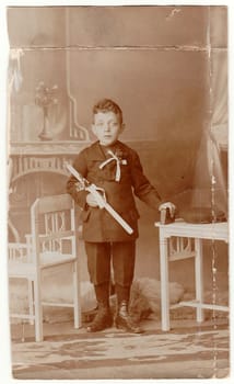 A vintage photo shows young boy - the first holy communion. Antique black white photo with sepia tint.