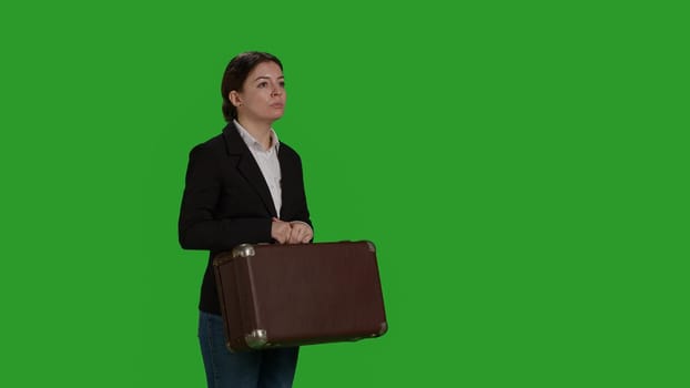 Side view of corporate worker carrying suitcase on camera