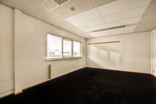 an empty room with a window and black carpet