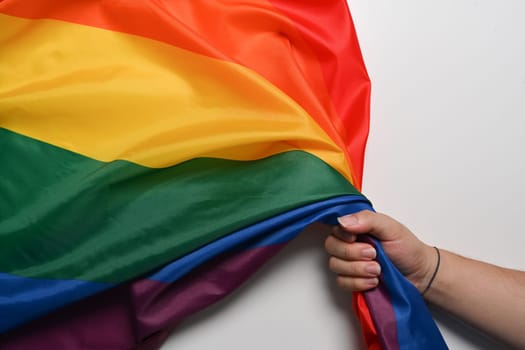 Man hand holding LGBT pride flag on white background. LGBT concept.